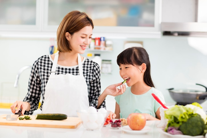 Happy mother and daughter cooking in the kitchen