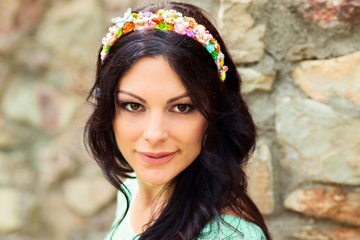 Spring  portrait to the happy woman in a hair band with flowers and butterflies