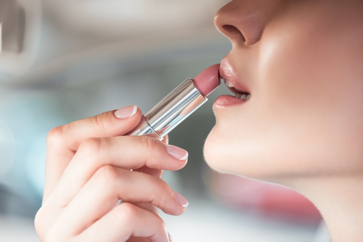 Cropped shot of a young woman applying a light pink lipstick