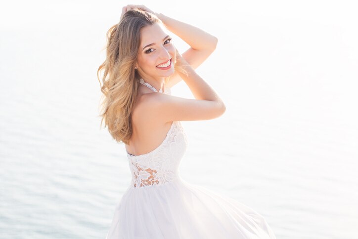 Beautiful smiling young bride girl is sitting over the sea view