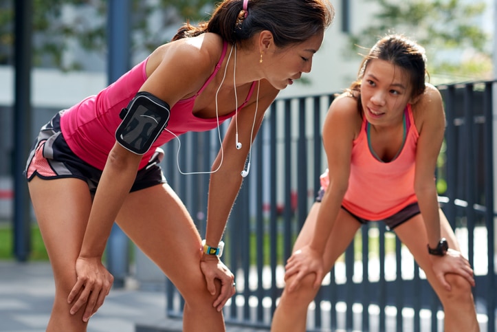 exhausted sporty asian chinese women runners after fitness running workout outdoors