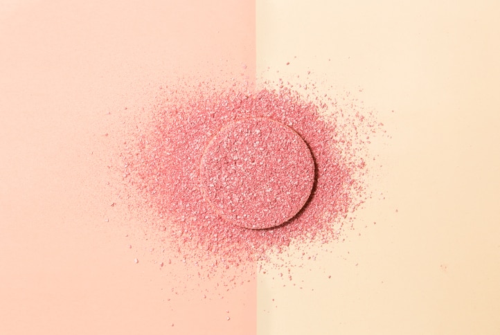 Powdered blush and sponge on double background of pink and beige