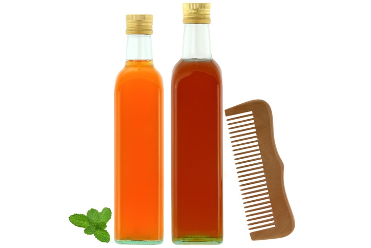 Bottles of raw and unfiltered organic apple cider vinegar with mother enzymes, organic honey next to wooden comb, ingredients for dry and damaged hair treatment isolated on white background