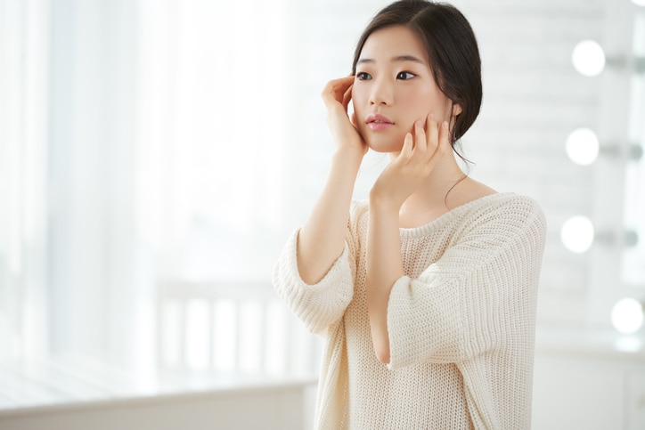 Korean young girl with perfect fresh skin touching her face