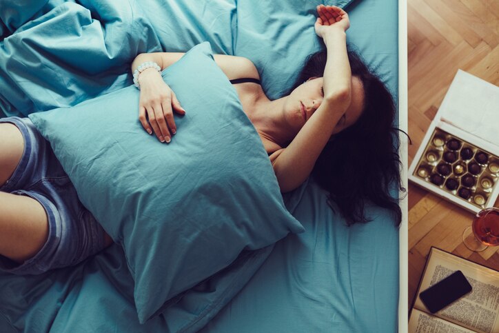 Depressed woman in bed with hand on forehead