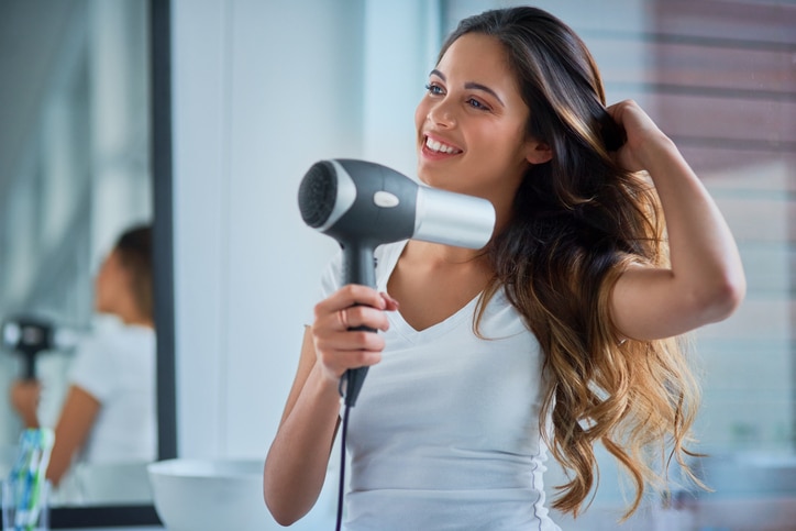 Shot of an attractive young woman blowdrying her hair in the bathroom