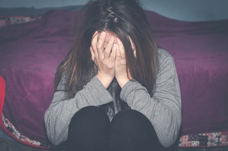 Depressed and lonely girl abused as young sitting alone in her room feeling miserable and anxiety cry over her life, dark image