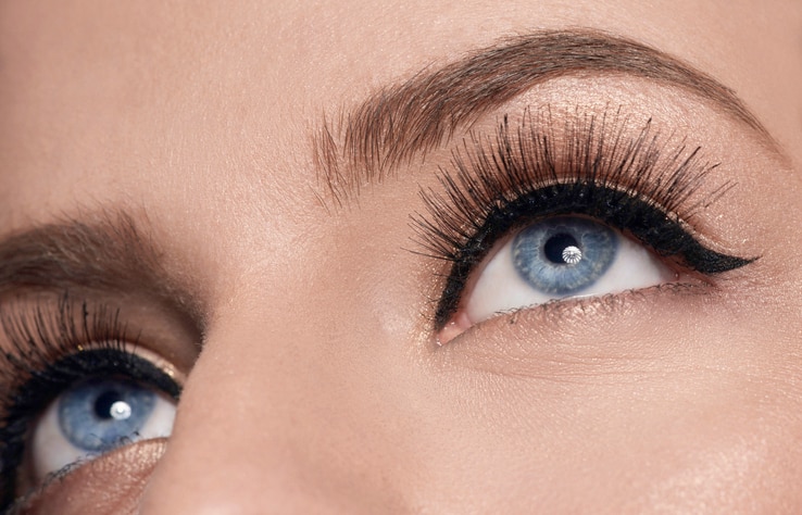 horizontal shot of woman with blue eyes looking up, false eyelashes on it.