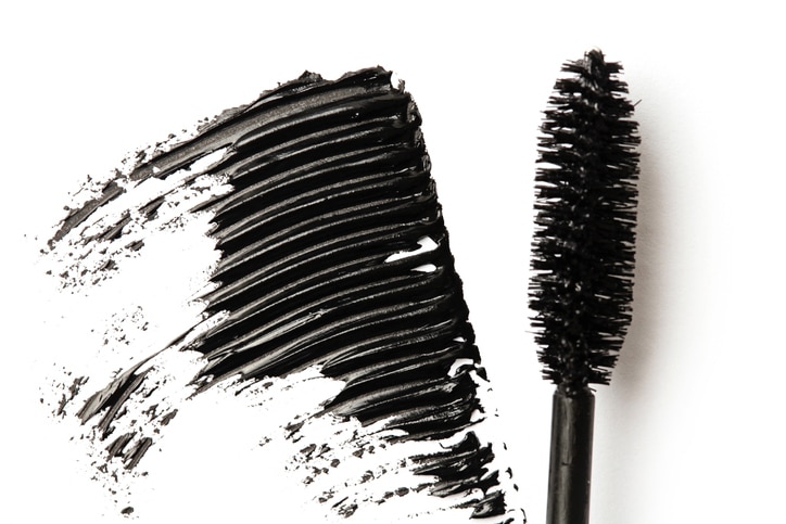 Black mascara stroke and make up brush isolated on white