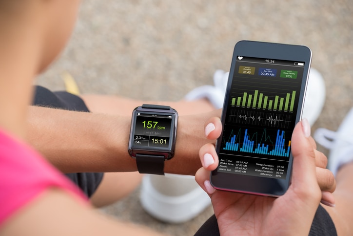 Female Runner Looking At Her Mobile And Smart Watch Heart Rate Monitor