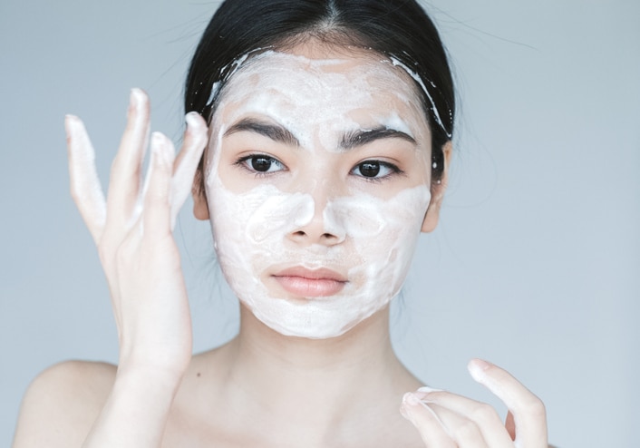 Young beautiful woman washing her face with hands by soap. Studio shot. Studio shot.