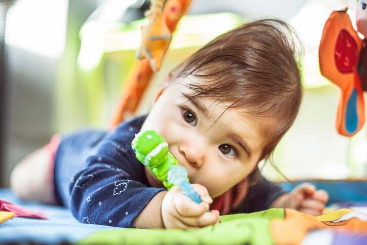 Baby chewing a teething toy in the baby gym