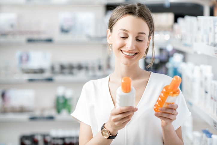 Young woman customer choosing sunscreen lotion at the pharmacy store