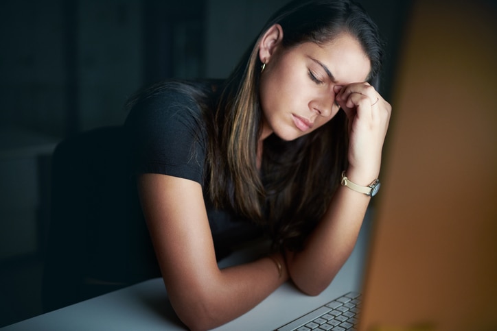 Shot of a young businesswoman looking stressed during a late night in a modern office