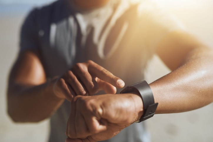 Closeup shot of an unrecognizable man checking his smartwatch while exercising outdoors