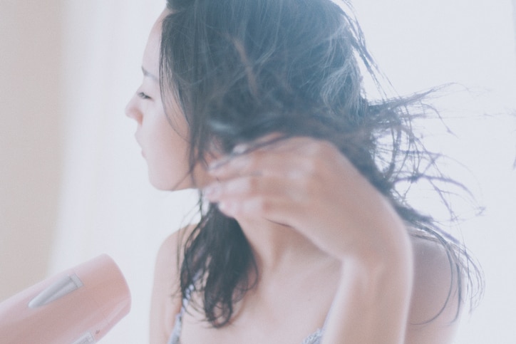 Woman drying her hair with a hair dryer at home in Japan