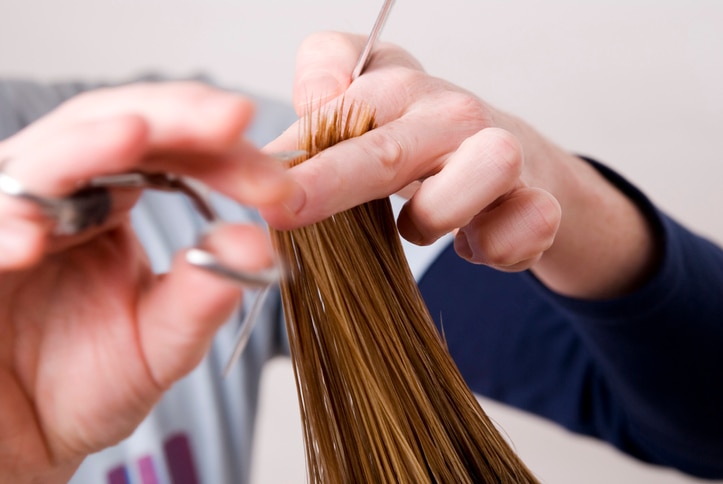 Spitzen schneiden beim Friseur mit HAnden im Vodergrund