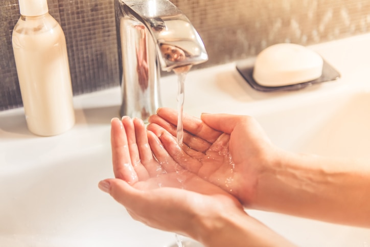 Cropped image of beautiful young woman washing her hands in the bathroom