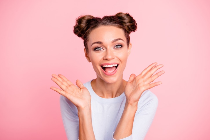 Close up photo of amazing attractive pretty she her lady with cute buns both hands pales up raised laugh laughter glad about prices wearing white pullover isolated on bright rose background