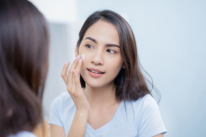 Asian women applying face lotion.