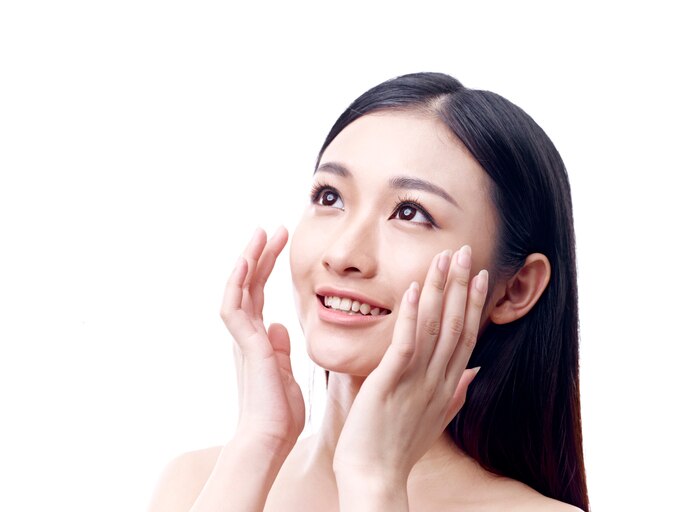 young asian woman rubbing face with hands, happy and smiling, isolated on white background.