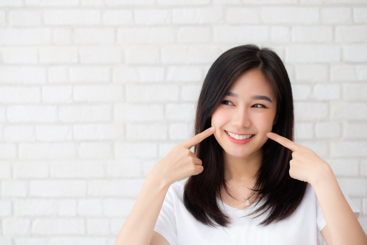 Portrait of beautiful young asian woman happiness standing finger touch cheek on gray cement texture grunge wall brick background, businesswoman is a smiling on concrete, business people concept.