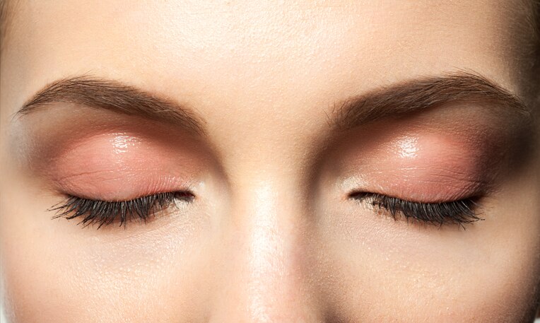 Close-up eyes closed with makeup with brown eyebrows and black lashes