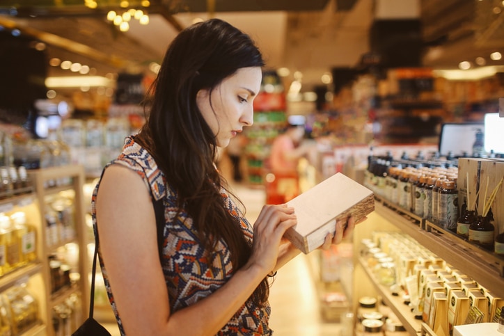 Image of a young brunette woman, browsing through the shelves of a Bangkok shopping mall, looking for natural cosmetics.