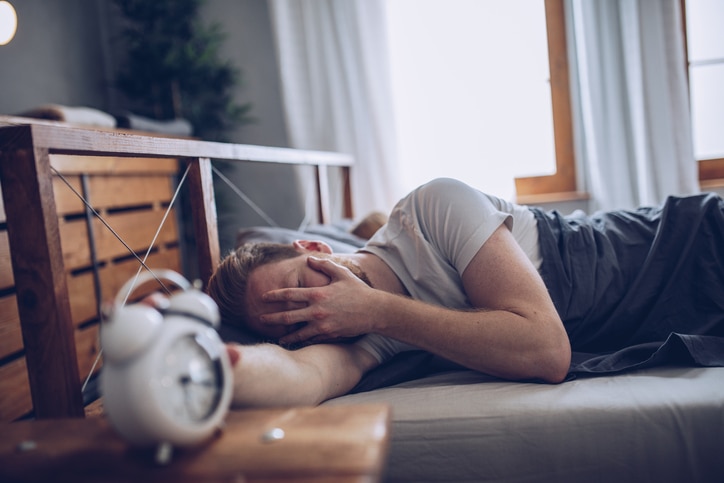 Sleeping man disturbed by alarm clock early in the morning