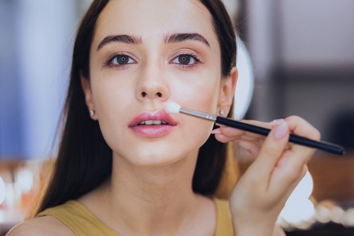 Green-eyed woman. Green-eyed appealing woman holding little face brush in her hand while getting ready for party