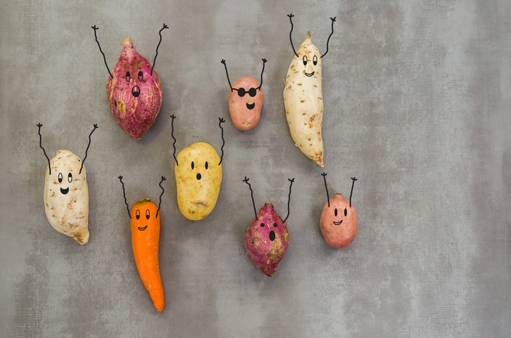 Great concept of healthy eating, vegetables with happy faces with arms up, potato, sweet potato, carrot. Gray background, polished concrete.