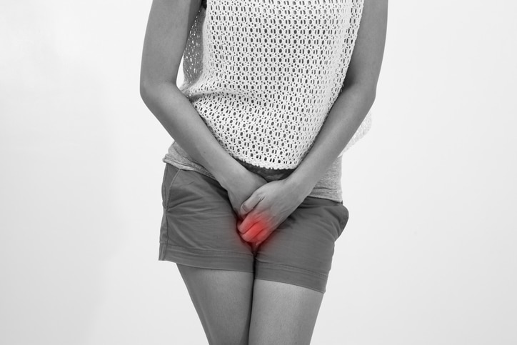 woman with hands holding her crotch isolated in a white background