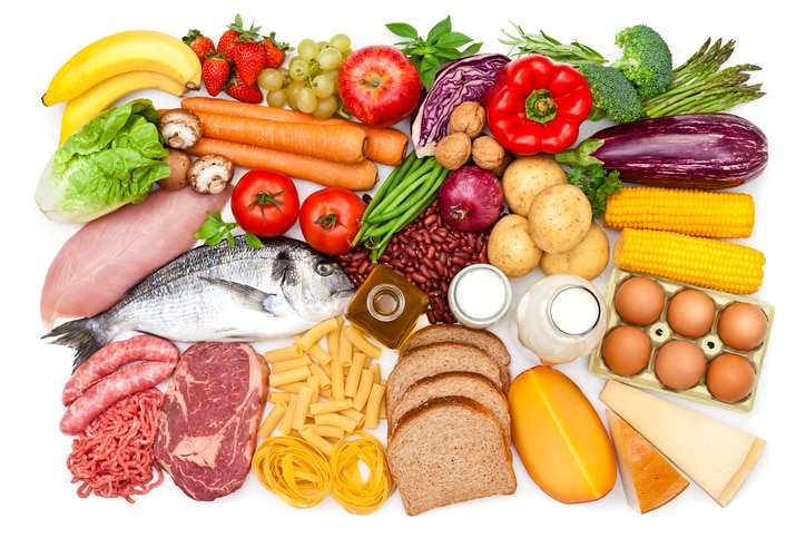 Top view of a white table filled with a large group of different types of food like carbohydrates, protein and dietary fiber. Food included in the composition are dairy products, sausages, minced meat, poultry, fish, bread, pasta, rice, beans, nuts, olive oil, fruits and vegetables. DSRL studio photo taken with Canon EOS 5D Mk II and Canon EF 70-200mm f/2.8L IS II USM Telephoto Zoom Lens