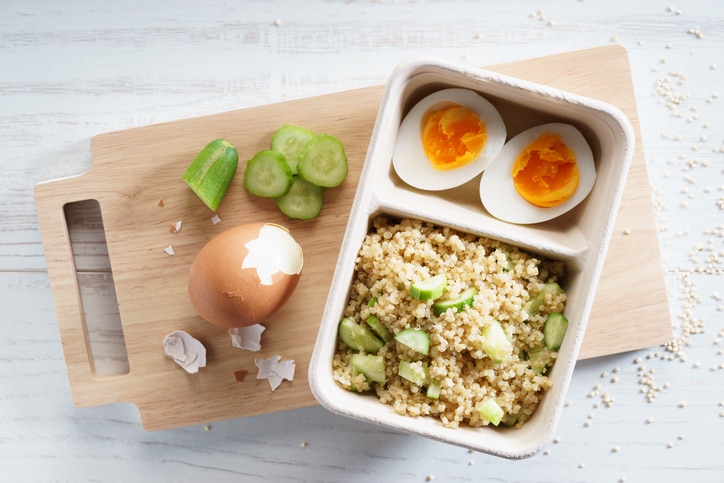 quinoa salad with boiled egg in paper food container, top view