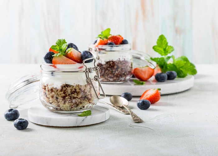 Gluten free breakfast with red quinoa, yogurt and berries in glass jar. Healthy super foods concept with copy space.