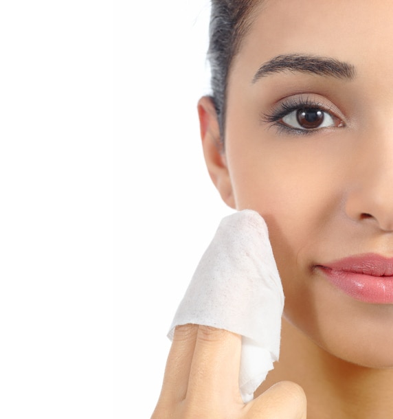 Close up of a woman face removing make up with a baby wipe isolated on a white background