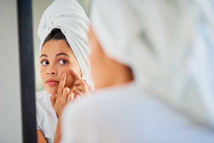 Shot of an attractive young woman squeezing a pimple on her face in the bathroom