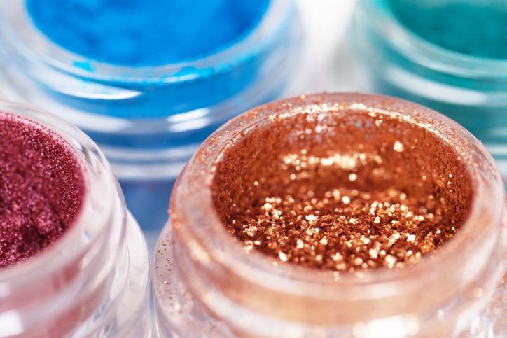 Set of glass jars with metallic glossy eye shadows on white background