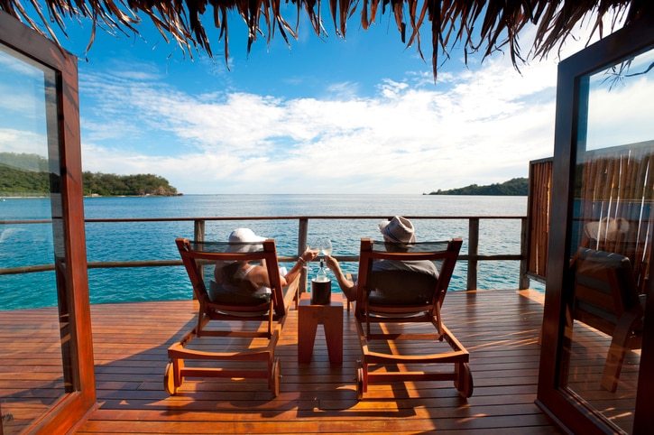 Couple relaxing on sun lounges in an over water bungalow