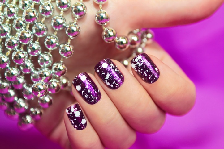 Snow manicure with the design of the white crumbs on violet brilliant varnish for the nails.