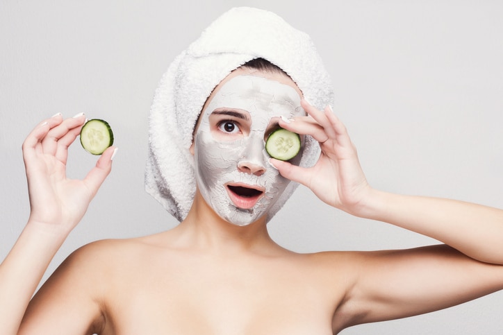 Skin care. Beautiful girl with collagen mask and cucumber slices on eyes against white background getting beauty tretment . Spa concept with copy space