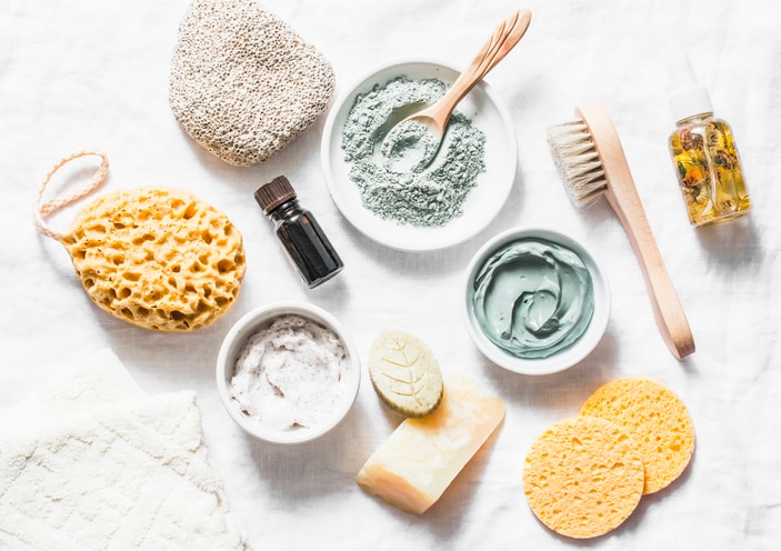 Spa accessories - nut scrub, sponge, facial brush, natural soap, clay face mask, pumice stone, essential oil on a light background, top view. Healthy lifestyle concept. Beauty, skin care. flat lay