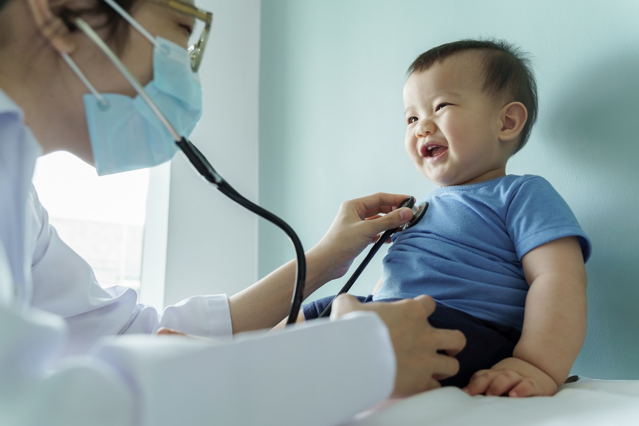 Asian female Pediatrician doctor examining little cute smiling Baby boy with stethoscope in medical room at hospital.