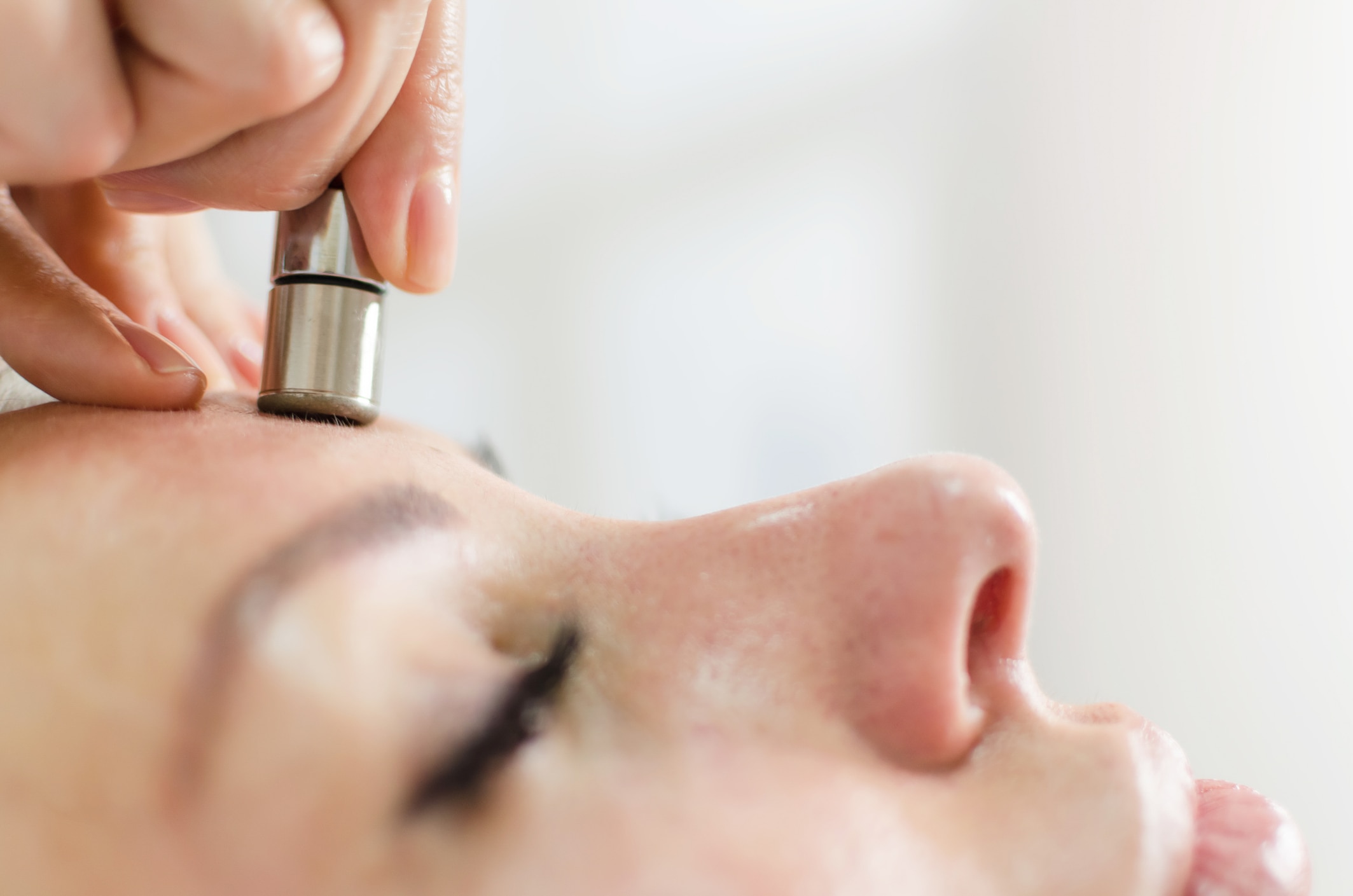 Hardware cosmetology. Closeup portrait of female face with closed eyes getting microdermabrasion procedure in a beauty parlour. Procedure of Microdermabrasion