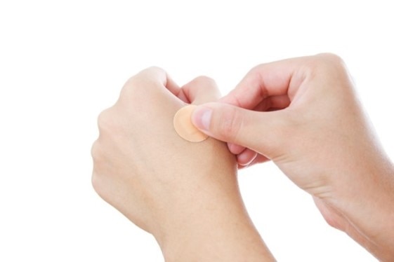 Bonding medicated plaster on woman's hand, isolated on a white background.