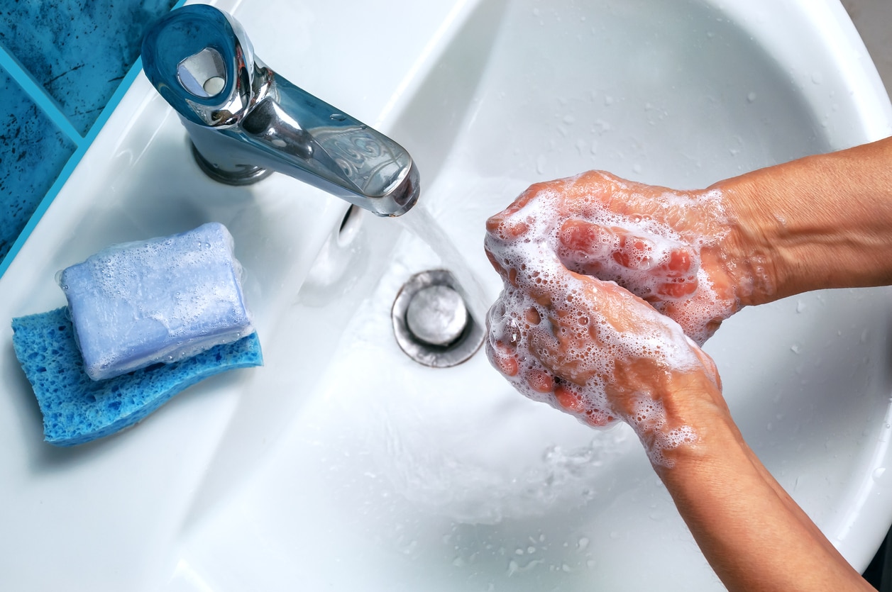 soapy hand over the washbasin and piece of blue soap