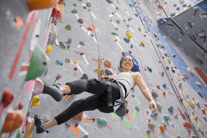 Smiling woman climbing indoor rock wall, MBTI 16 Personalities –  popular leisure activities for ISTP